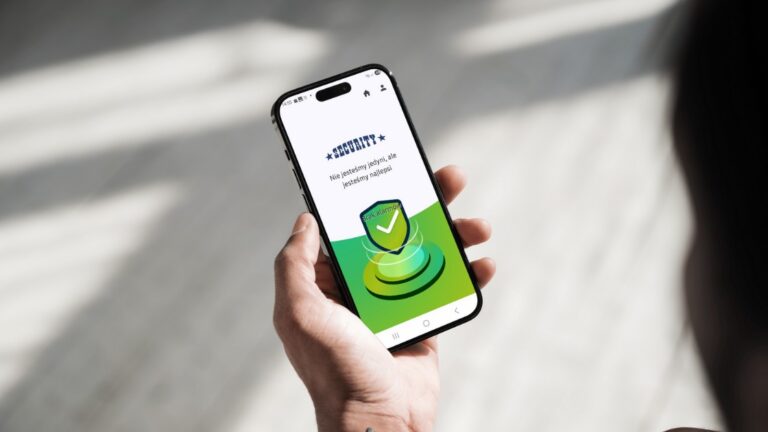 Osoba trzymająca smartfon z uruchomioną aplikacją Monpatrol, na ekranie widoczny komunikat "Brak alarmu" i logo SECURITY.